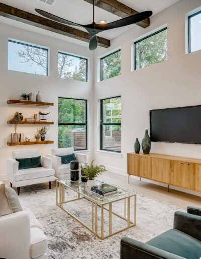Bright modern living room with large windows, contemporary furniture, and a television on the wall.