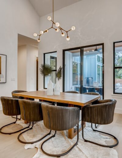 Modern dining room with a wooden table, leather chairs, and an artistic chandelier.
