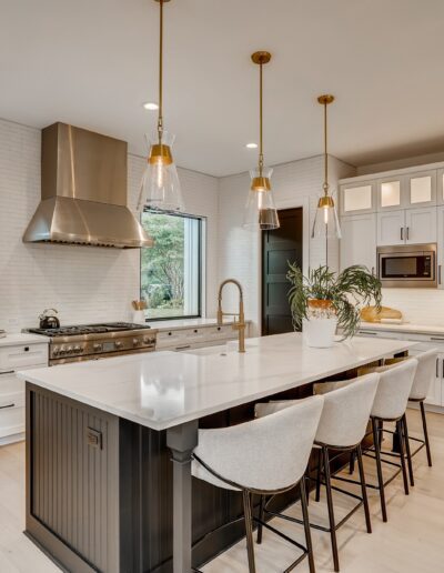 Modern kitchen interior with white cabinetry, stainless steel appliances, and a central island with bar stools.