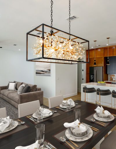Modern dining and living room interior with elegant chandelier, wooden cabinetry, and contemporary furnishings.