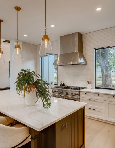 A modern kitchen interior featuring a large island with seating, stainless steel appliances, and pendant lighting.