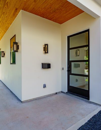Modern house entrance with a wood-panel ceiling and decorative wall sconces.