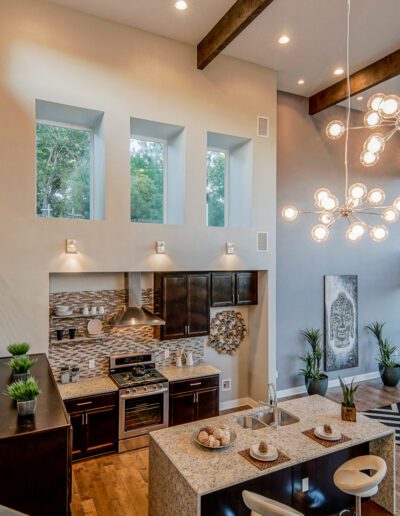 Modern open-concept kitchen and living area with high ceilings, large windows, and stylish pendant lighting.