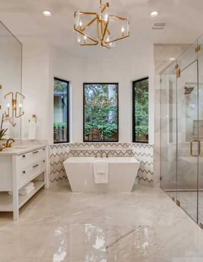 A modern bathroom with herringbone patterned tiles, a walk-in shower, and gold accents.