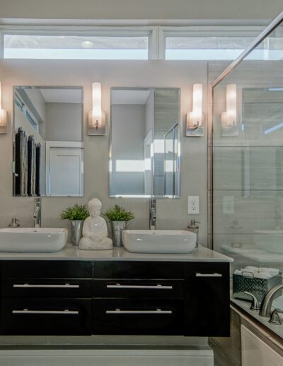 Modern bathroom with dual vessel sinks, large mirror, and glass-enclosed shower.