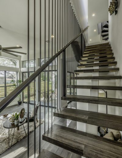 Modern staircase with floating wooden steps and vertical metal balusters in a stylish interior.