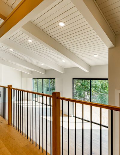 Spacious and bright upper-level interior with wooden floors, white ceilings, and large windows.