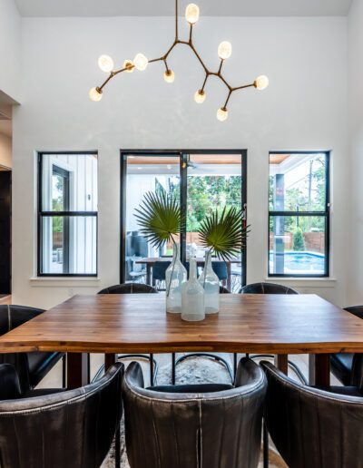 Modern dining room with a wooden table, leather chairs, and a chic chandelier.