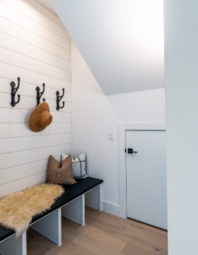 Modern hallway nook with a bench, coat hooks, and a cushion under a sloped ceiling.