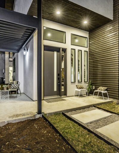 Modern home entrance with outdoor seating area, illuminated at night.