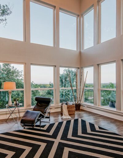 Spacious living room with high ceilings, large windows, and a view of the outdoors.