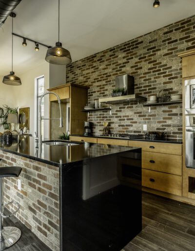 Modern kitchen with exposed brick walls, stainless steel appliances, and a central island with bar stools.