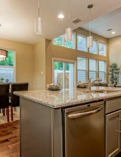 Modern kitchen interior with granite countertops, stainless steel appliances, and adjacent dining area.