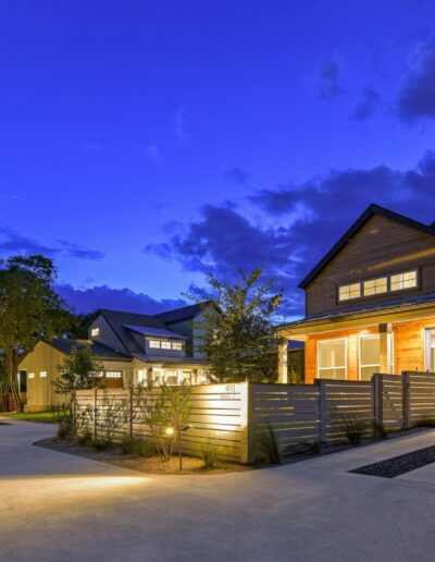 Modern residential homes illuminated at dusk with driveway and landscaped front yards.