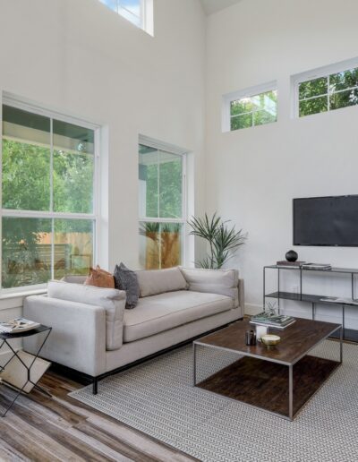 Bright living room with high ceilings, modern furniture, and a mounted television.