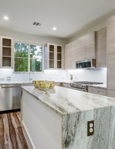 Modern kitchen interior with wooden cabinets and a marble countertop.