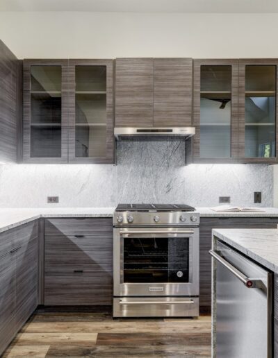 Modern kitchen interior with stainless steel appliances, gray cabinetry, and white countertops.